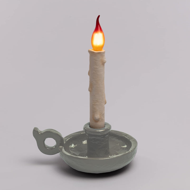 Seletti Bugia LED Candle Lamp White, pale gray-white base on a gray backdrop, flame bulb glowing
