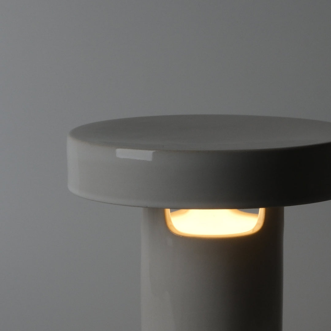 Glossy white ceramic table lamp with warm ambient glow, minimalist design