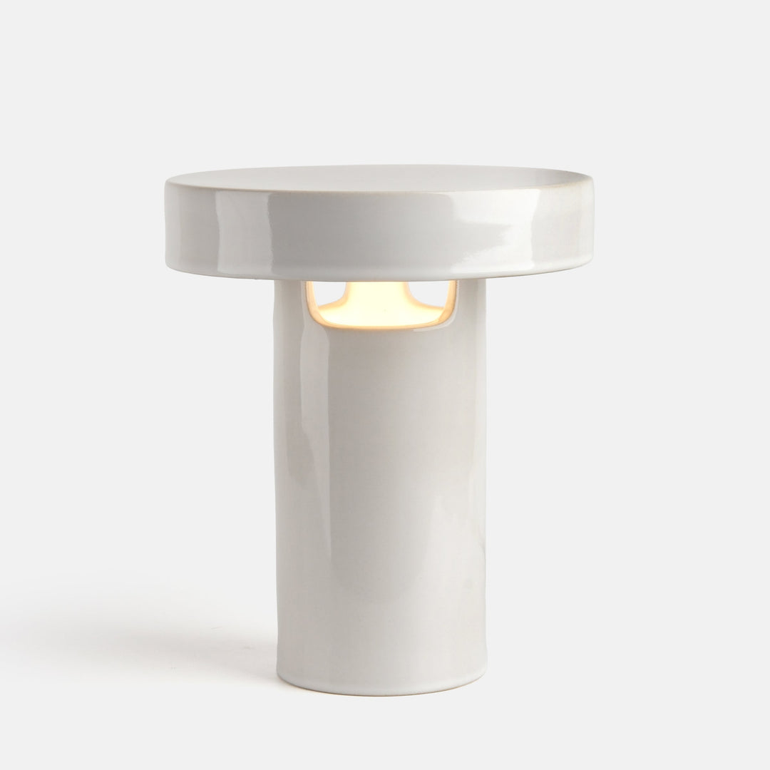 White ceramic table lamp with minimalist design and warm glow, featuring clean lines and modern aesthetic